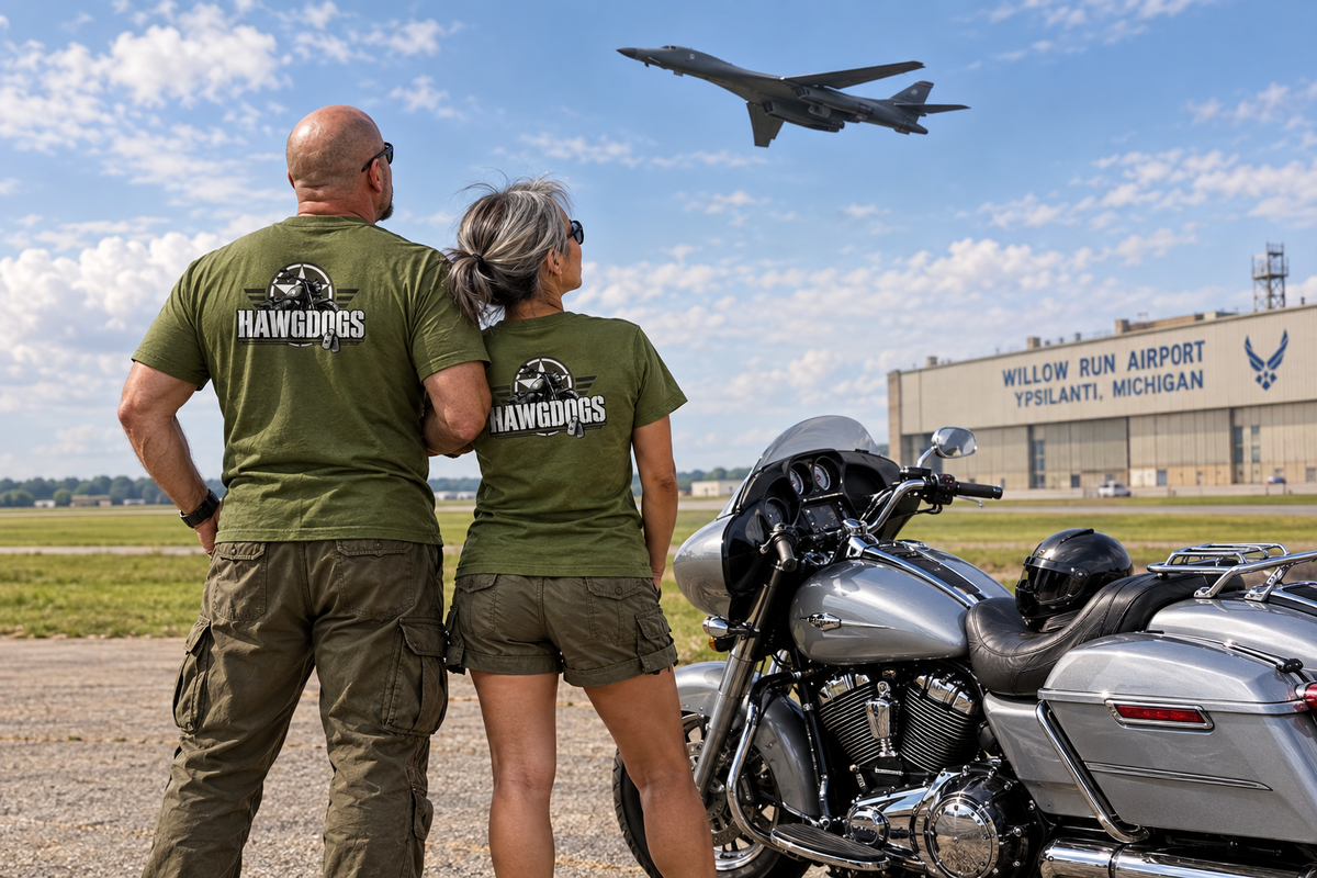 Couple in military green Might of The Republic tees at an airfield with a jet overhead