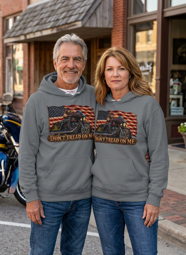 Couple in gray Don't Tread Doggo premium hoodies outside a small town shop
