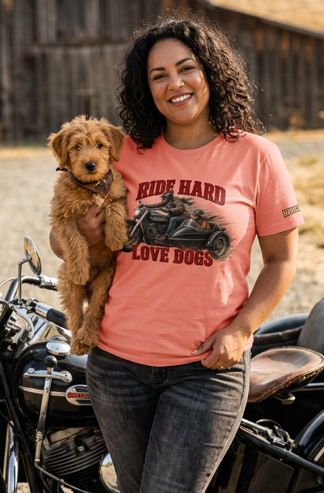 Woman in the pink Ride Hard & Love Dogs tee holding a doodle beside a motorcycle