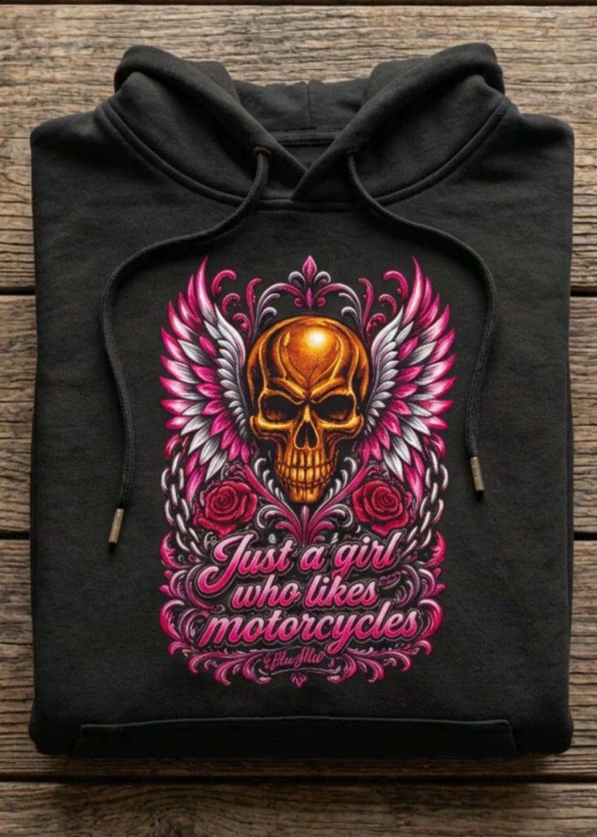 Front of the black Just A Girl Who Likes Motorcycles women's premium hoodie with the winged skull graphic, laid flat on a wooden table