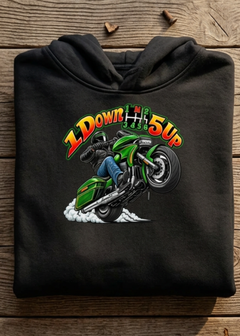 Front of the black Wild Wheelie 1 Down 5 Up hoodie with the 1 Down 5 Up wheelie graphic, laid flat on a wooden table