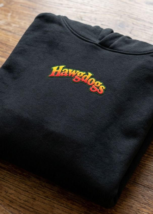 Back of the black Wild Wheelie 1 Down 5 Up hoodie with the Hawgdogs logo, folded on a wooden table