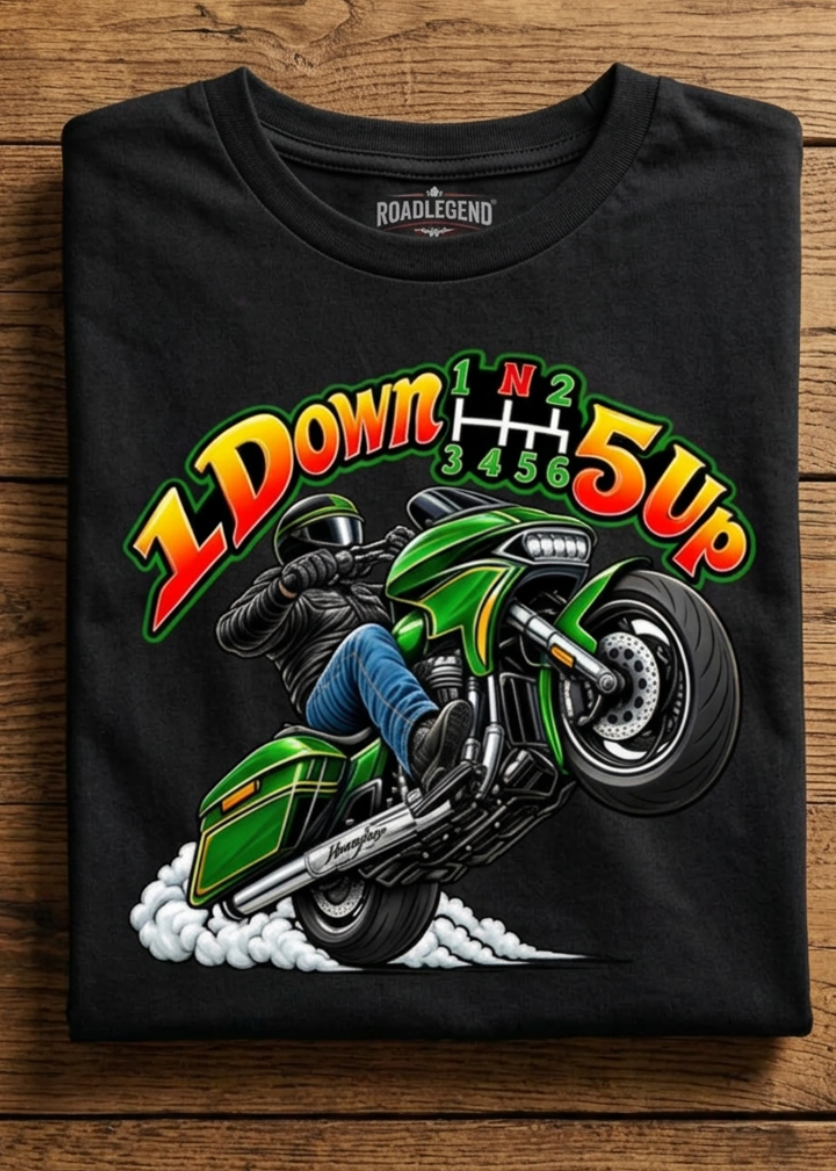 Front of the black Wild Wheelie 1 Down 5 Up tee with the 1 Down 5 Up wheelie graphic, laid flat on a wooden table